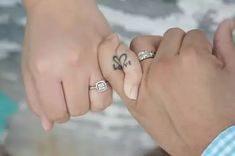 two people holding hands with tattoos on their fingers and one is holding the other's hand