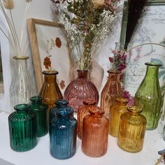 there are many different colored vases on the table