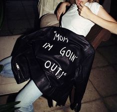 a woman sitting in a chair with a leather bag on her lap and writing on the back