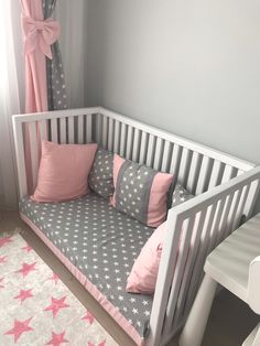 a white crib with pink and gray bedding