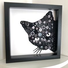 a black and white photo of a bird made out of buttons in a shadow box