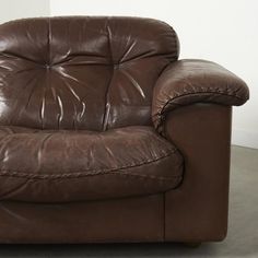 a brown leather chair sitting on top of a cement floor