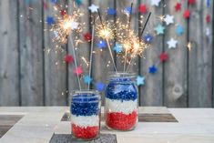 two mason jars filled with red, white and blue fireworks on top of a wooden table