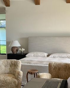 a laptop computer sitting on top of a bed in a bedroom next to two chairs