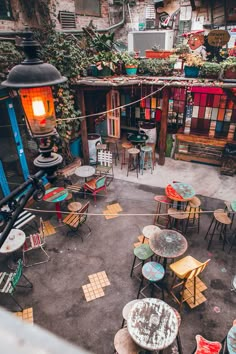 an overhead view of tables and chairs on the ground in front of a building with lots of plants