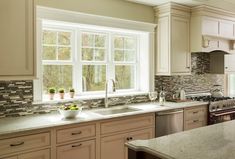 a large kitchen with white cabinets and marble counter tops, along with stainless steel appliances