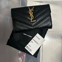 a black saint laurent wallet sitting on top of a bag