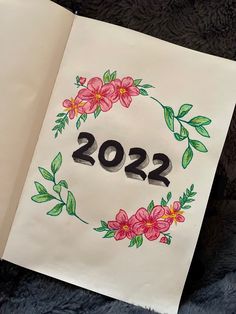 an open book with flowers on it and the number 2012 written in black ink, sitting on a fur surface