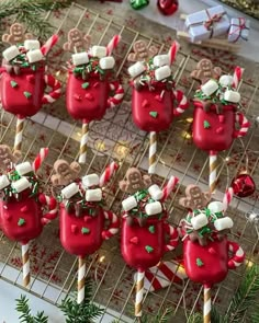 some red cups with marshmallows and candy canes on them sitting on a table