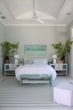 a bedroom with white furniture and green plants