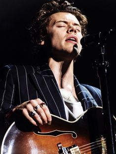 a man with his eyes closed while playing an acoustic guitar