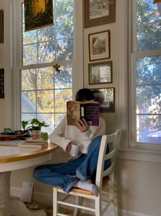 a person sitting at a table with a book in front of their face, reading