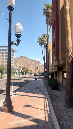 a lamp post on the side of a street with palm trees in the background,