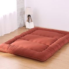 an orange dog bed is on the floor in front of a white wall and window