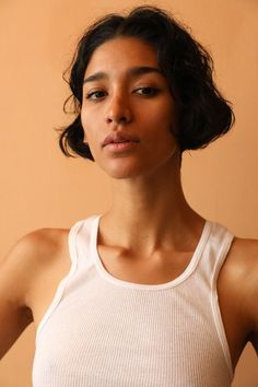 a woman in a white tank top posing for the camera