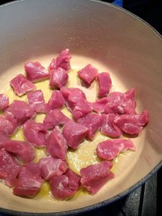 meat cooking in a pan on top of the stove with yellow liquid and seasoning