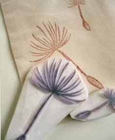 a white cloth with purple flowers on it next to a pair of scissors and a bag