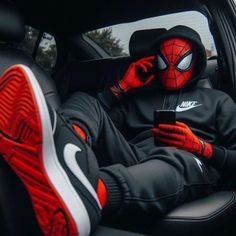 a spider man sitting in the back seat of a car while holding a cell phone