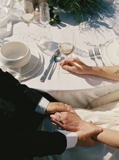 the bride and groom are holding hands at the table