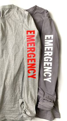 two long sleeved shirts with the words emergency and emergency printed on them, sitting next to each other