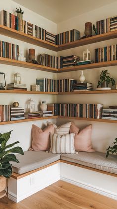 a room with bookshelves filled with lots of books and plants on the shelves