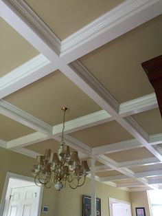 a chandelier hanging from the ceiling in a room with beige walls and white trim