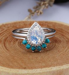 a pear shaped diamond ring with turquoise stones on it's sides and an oval band around the band