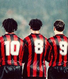 three men in black and red soccer uniforms looking at the sky with clouds behind them