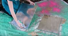 a woman is painting a piece of metal with pink and green paint on the surface