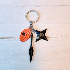 an orange and black star shaped keychain hanging from a metal hook on a white wooden surface