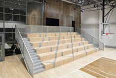 an indoor basketball court with wooden steps and metal railings