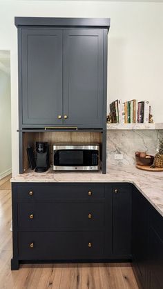 a kitchen with black cabinets and marble counter tops