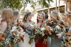 a group of women standing next to each other holding bouquets in their hands and laughing