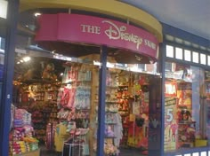 a store front with many items on display in it's glass window displays the logo for the disney store