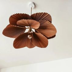 a ceiling light made out of brown paper petals hanging from the ceiling in a room