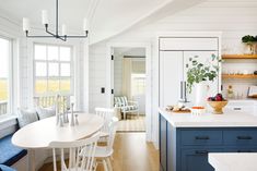 a kitchen with blue cabinets and white counter tops next to a breakfast nook filled with food