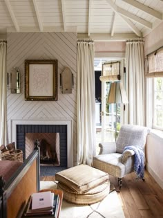 a living room filled with furniture and a fire place next to a window covered in curtains