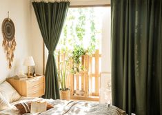 a bed room with a neatly made bed next to a wooden dresser and window covered in green curtains