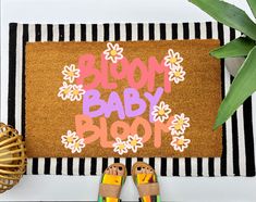 a door mat with the words bloom baby bloom on it next to two pairs of sandals