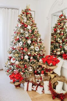 two christmas trees decorated with red, white and gold ornaments in front of a mirror