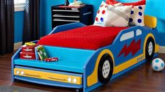 a child's bedroom with blue walls and wooden flooring has a race car bed