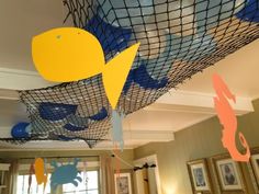 the room is decorated with blue, yellow and orange paper fish net hanging from the ceiling