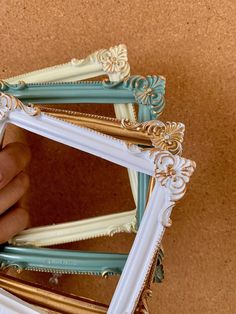 a hand holding a small white and gold framed mirror