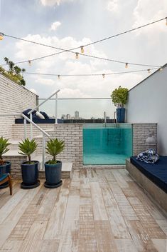 an outdoor swimming pool on the roof of a building with potted plants and lights