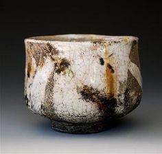 a close up of a bowl on a gray surface with black and white paint splattered all over it