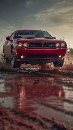 a red sports car driving through mud on a dirt road in the sunset or sunrise