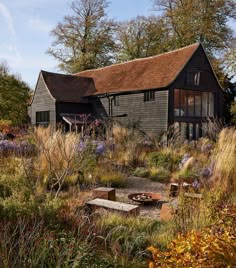 an old barn sits in the middle of a field full of tall grass and wildflowers