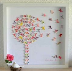 a white frame with paper cut butterflies on it and a pink rose next to it