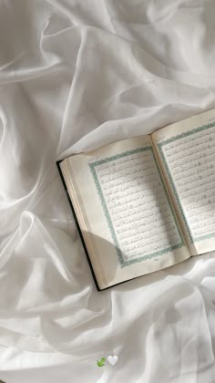 an open book sitting on top of a white sheet