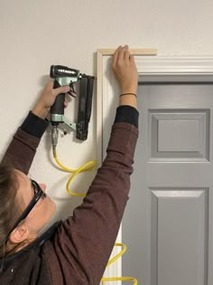 a woman working on a door with a driller and power strip attached to it